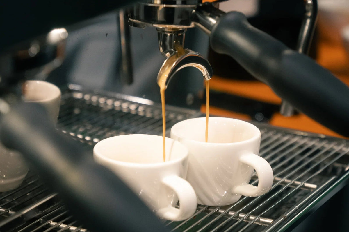 Detailshot, Espresso läuft aus Siebträger in Tassen